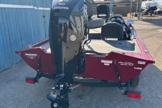 Slide: The Image of 2023 Tracker Pro Team 175 TF boat, red, with outboard motor, parked near blue building. - 4