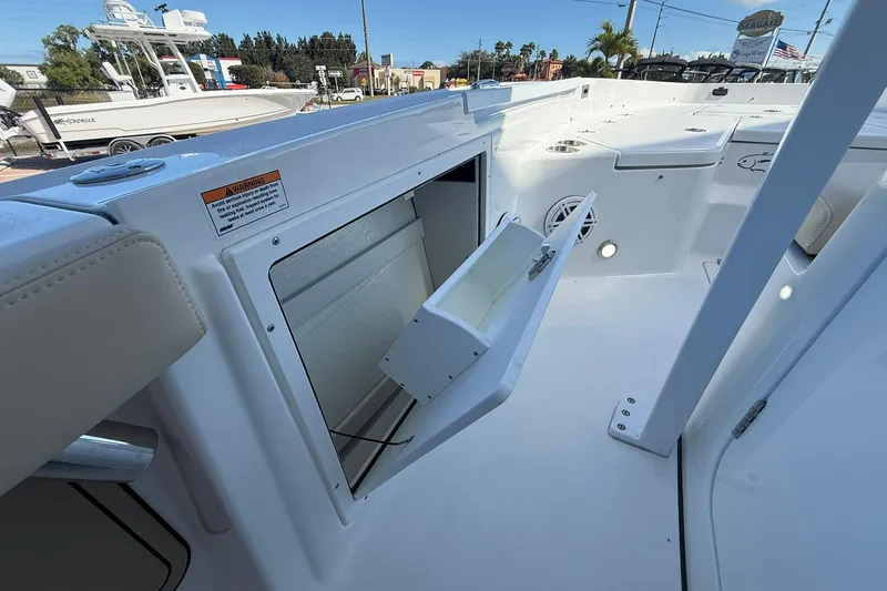 Slide: The Image of 2026 Crevalle 24 HCO boat interior with open storage compartment, white seating, and deck. - 23