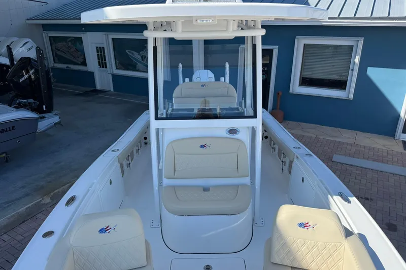 Slide: The Image of 2026 Crevalle 24 HCO boat with beige seating, docked near a blue building. - 30