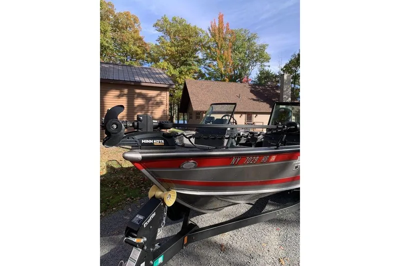 Slide: The Image of 2022 Lund 1875 Pro-V Sport boat on trailer, parked near a house with autumn trees. - 10