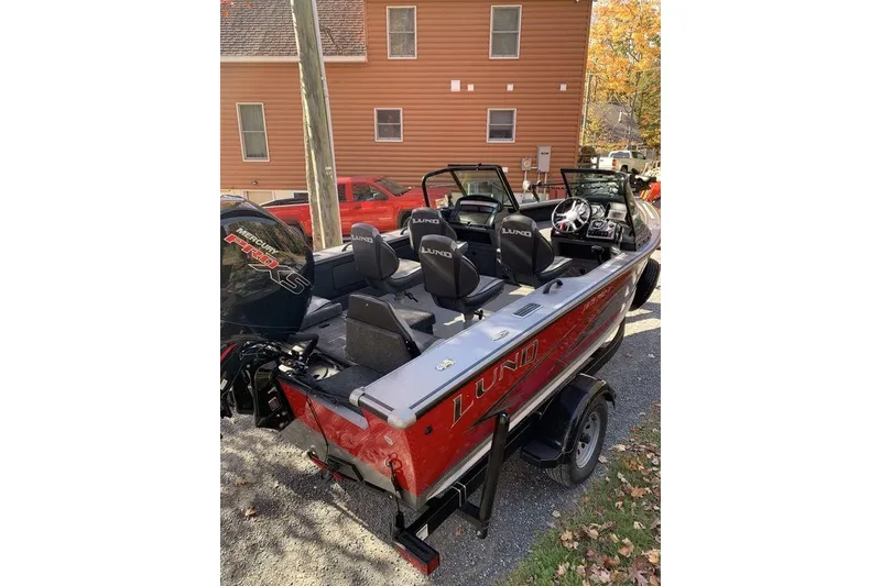 Slide: The Image of 2022 Lund 1875 Pro-V Sport boat with Mercury engine, parked outdoors. - 2