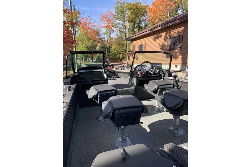 Slide: The Image of 2022 Lund 1875 Pro-V Sport boat interior with seating, surrounded by autumn trees. - 5