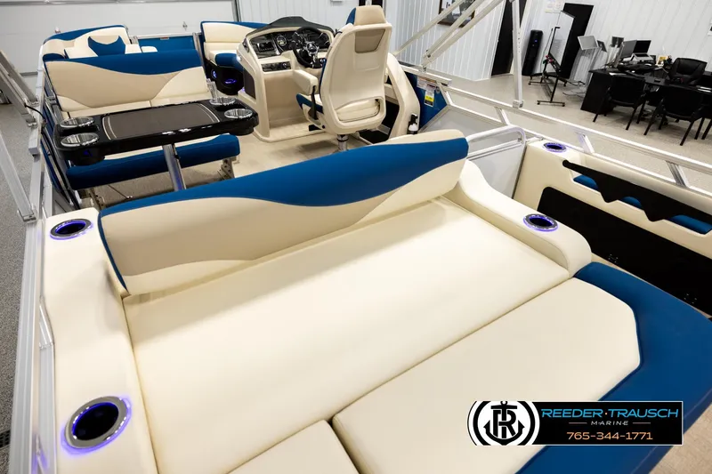 Slide: The Image of 2026 Avalon LSZ ENT pontoon boat interior with beige and blue seating, cup holders, and control console. - 11