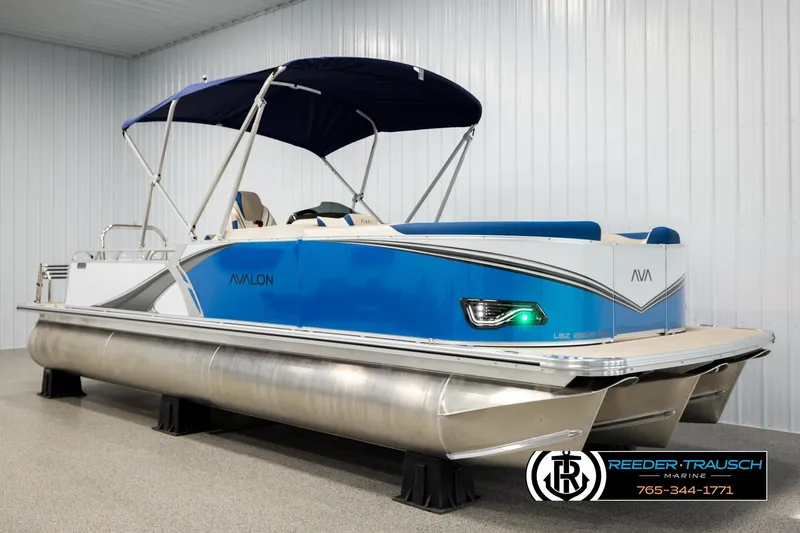 Slide: The Image of 2026 Avalon LSZ ENT pontoon boat with blue exterior and canopy in showroom. - 3