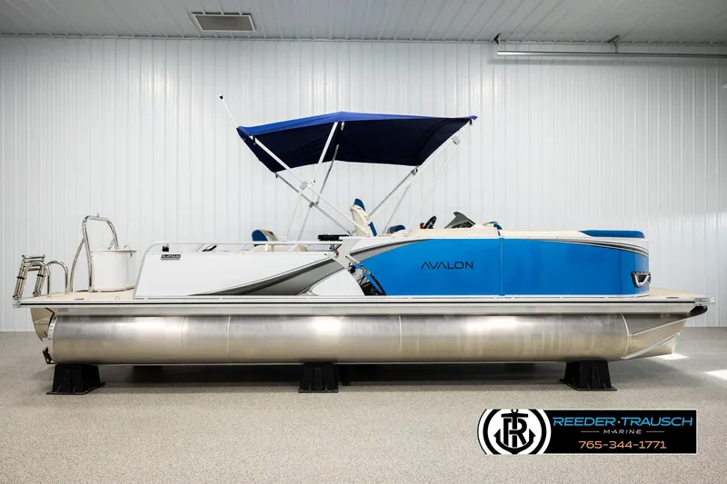 Slide: The Image of 2026 Avalon LSZ ENT pontoon boat with blue canopy in showroom. - 5