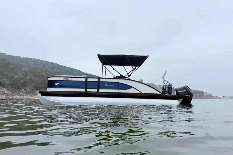 The Image of 2020 Barletta L23UC pontoon boat on a calm lake with scenic background. - 1