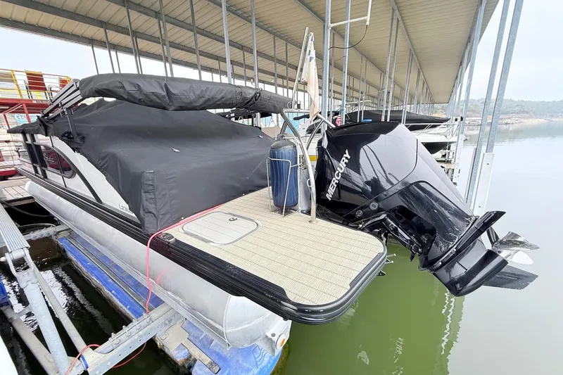 Slide: The Image of 2020 Barletta L23UC pontoon boat with Mercury outboard motor, docked under a covered marina. - 10