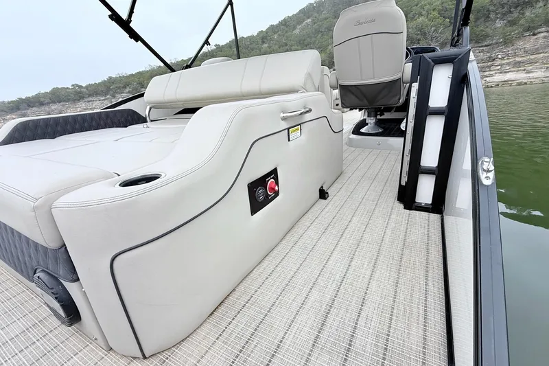 Slide: The Image of 2020 Barletta L23UC pontoon boat interior with seating and helm, on a calm lake. - 18