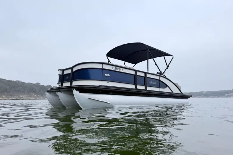 Slide: The Image of 2020 Barletta L23UC pontoon boat on calm water with canopy. - 2