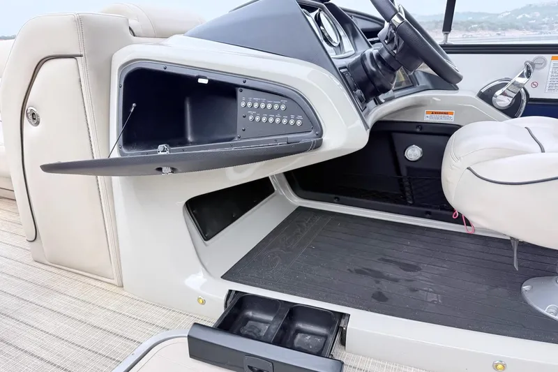 Slide: The Image of 2020 Barletta L23UC boat interior with open storage compartment and steering wheel. - 24