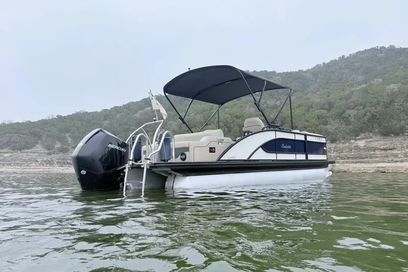 Slide: The Image of 2020 Barletta L23UC pontoon boat on a lake with scenic hillside background. - 5