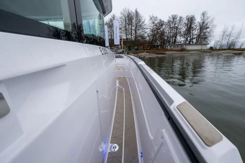 Slide: The Image of 2027 Axopar 38 Cross Cabin boat docked by a serene lakeside. - 23