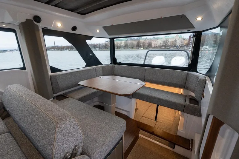 Slide: The Image of Interior of 2027 Axopar 38 Cross Cabin with modern seating and table, overlooking water. - 29