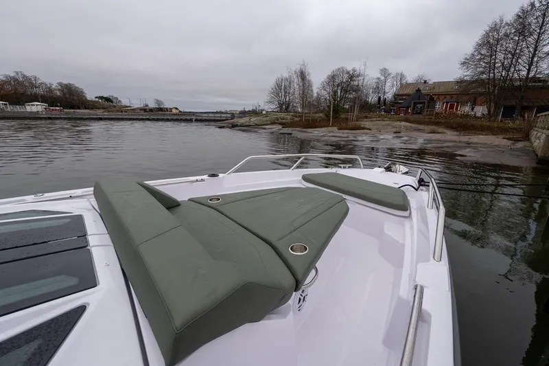 Slide: The Image of 2027 Axopar 38 Cross Cabin boat with green seating, docked near a scenic shoreline. - 84