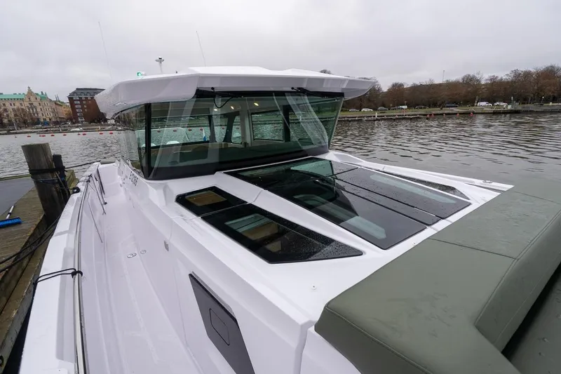 Slide: The Image of 2027 Axopar 38 Cross Cabin boat docked by a calm waterfront. - 88