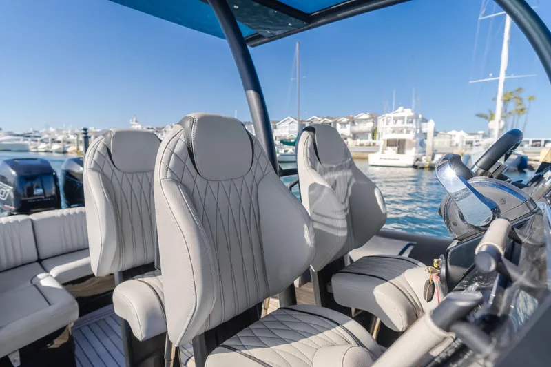 Slide: The Image of 2019 Technohull Sea DNA 999 boat interior with luxurious seating and steering wheel, docked at marina. - 24