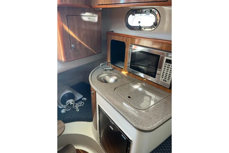Slide: The Image of 2007 Pursuit OS 285 Offshore boat interior with kitchenette, sink, microwave, and storage. - 13