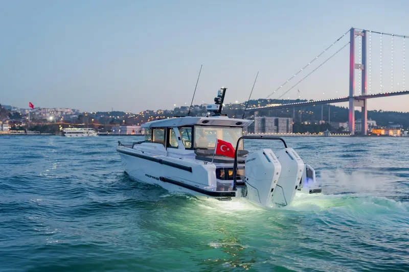 Slide: The Image of 2026 Axopar 38 Cross Cabin cruising near illuminated bridge at dusk. - 15