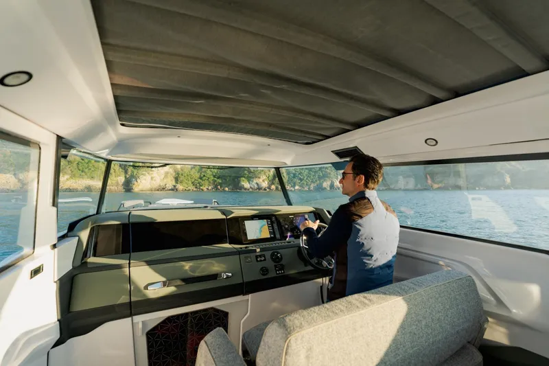 Slide: The Image of Interior view of 2026 Axopar 38 Cross Cabin with driver navigating on water. - 8