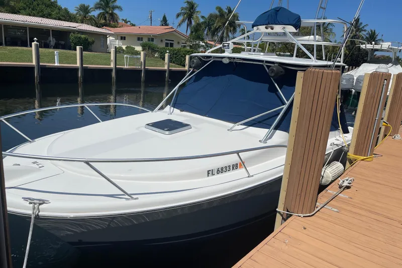 Slide: The Image of 2007 Luhrs 28 Open boat docked, featuring sleek design and blue canopy. - 89