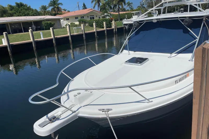 Slide: The Image of 2007 Luhrs 28 Open boat docked by waterfront homes, featuring sleek design and blue canopy. - 93