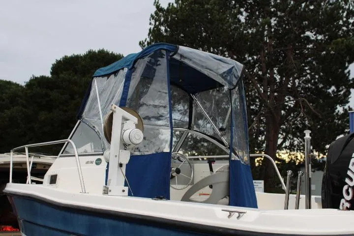 Slide: The Image of 2010 Trophy 1802 Walkaround boat with blue canopy, parked outdoors. - 8
