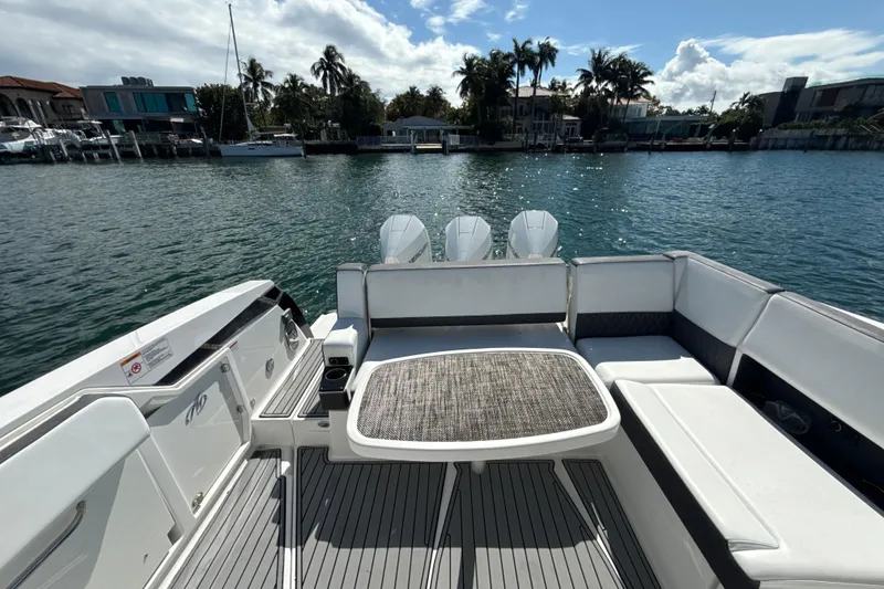 Slide: The Image of 2019 Monterey 385 Super Express boat interior with seating and table, overlooking waterfront homes. - 7