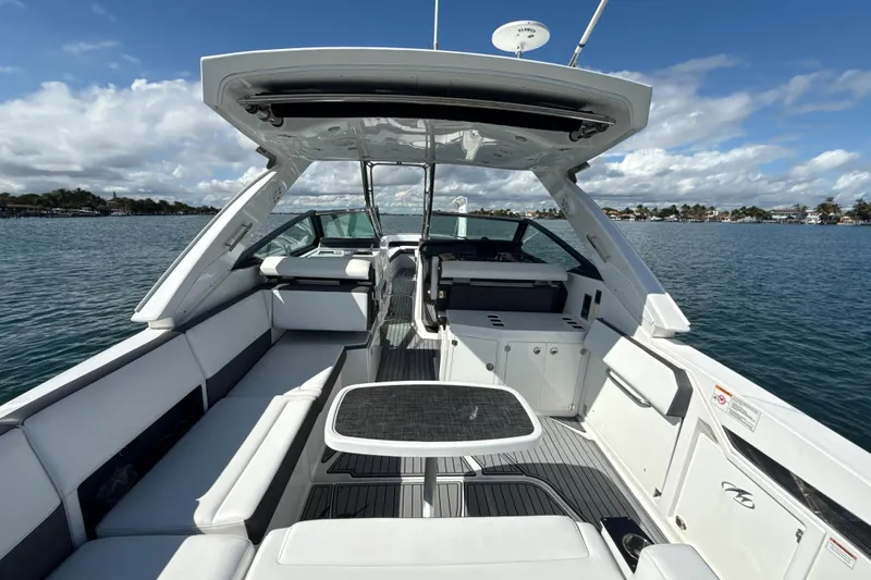 Slide: The Image of 2019 Monterey 385 Super Express boat interior with seating and table on a sunny day. - 8