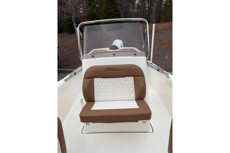 Slide: The Image of 2026 Pioneer 180 Islander boat with brown and white seating, outdoors. - 6
