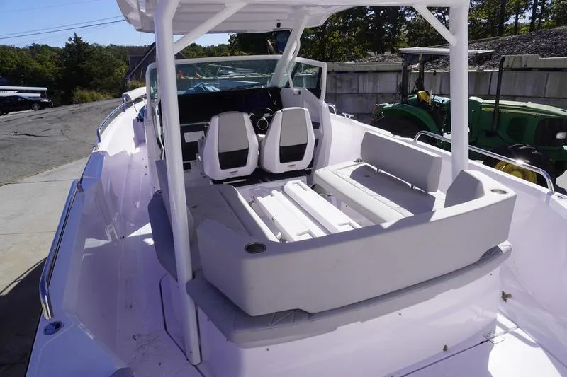 Slide: The Image of 2025 Axopar 29 Sun-Top boat interior with seating and helm, docked outdoors. - 17