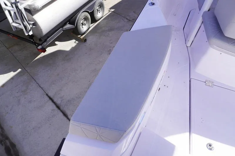 Slide: The Image of 2025 Axopar 29 Sun-Top boat interior with gray seating and trailer in background. - 20