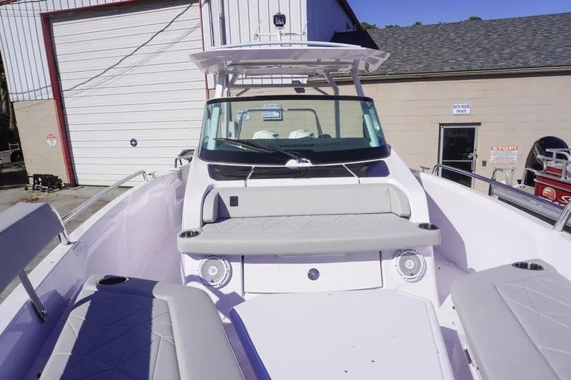 Slide: The Image of 2025 Axopar 29 Sun-Top boat with spacious seating and modern design in a marina setting. - 8