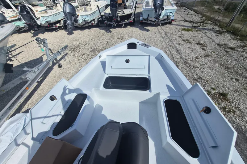 Slide: The Image of 2026 Xpress H20B Bay boat interior with storage compartments, parked among other boats. - 10