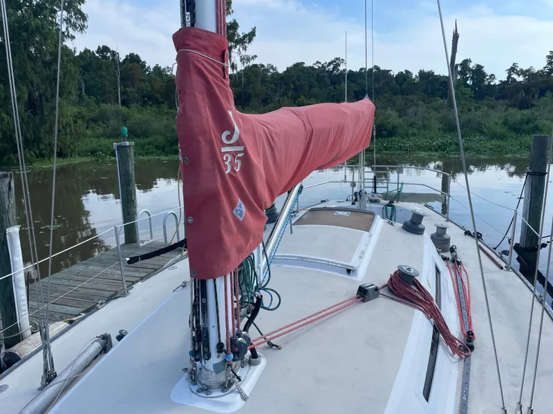 Slide: The Image of 1983 J Boats J/35 sailboat docked by a tranquil riverside. - 4