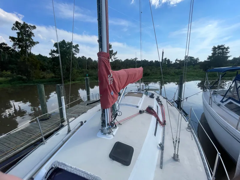 Slide: The Image of 1983 J Boats J/35 sailboat docked by a calm riverbank. - 5