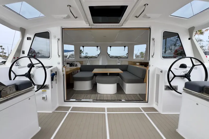 Slide: The Image of 2023 Seawind 1170 catamaran interior with dual steering wheels and spacious seating area. - 20
