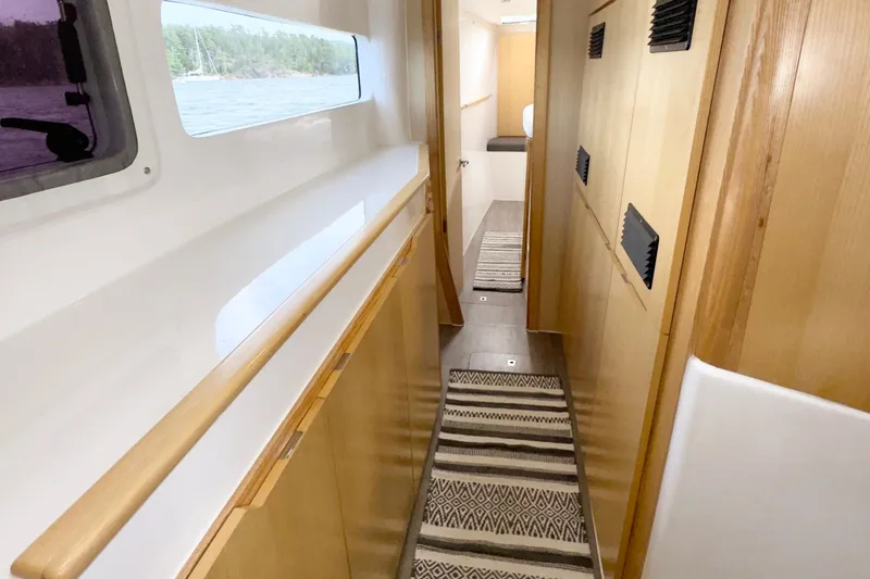 Slide: The Image of Narrow hallway inside 2023 Seawind 1170 yacht, featuring wooden cabinetry and striped rugs. - 27