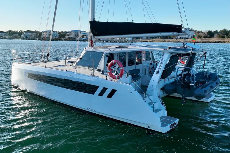 Slide: The Image of 2023 Seawind 1170 catamaran sailing on calm waters near coastal homes. - 5