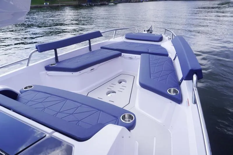 Slide: The Image of 2025 Axopar 29 XC Cross Cabin boat with blue seating on calm water. - 16