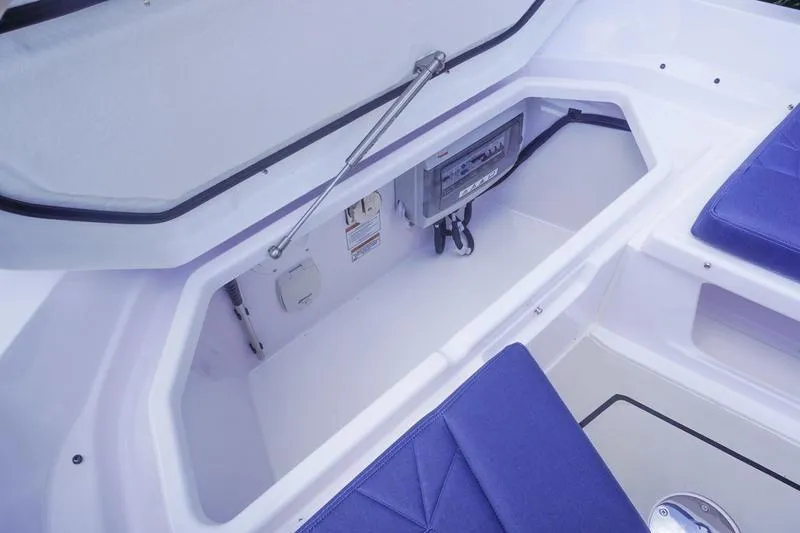 Slide: The Image of 2025 Axopar 29 XC Cross Cabin storage compartment with blue seating and control panel. - 18