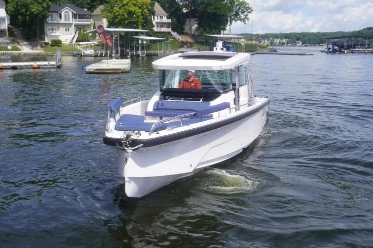 Slide: The Image of 2025 Axopar 29 XC Cross Cabin boat cruising on a scenic lake. - 2