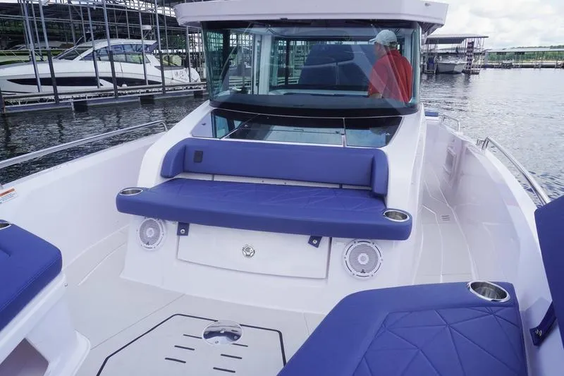 Slide: The Image of 2025 Axopar 29 XC Cross Cabin boat with blue seating, docked at marina. - 20