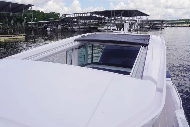 Slide: The Image of 2025 Axopar 29 XC Cross Cabin boat with open sunroof at marina. - 21