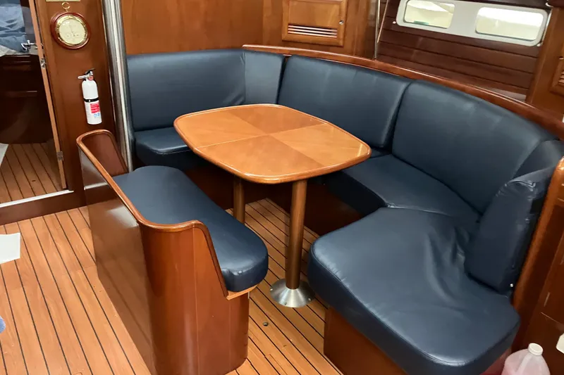 Slide: The Image of Interior of 2005 Beneteau Oceanis 423 yacht with wooden dining area and blue seating. - 4