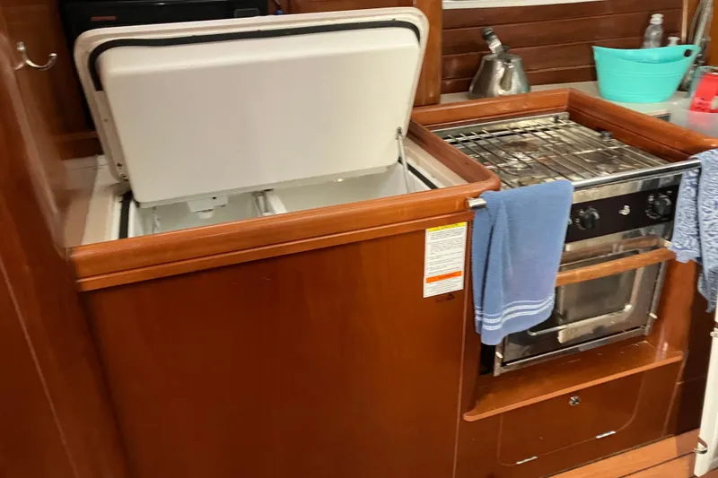 Slide: The Image of Galley kitchen in 2005 Beneteau Oceanis 423 sailboat with stove and open fridge. - 8