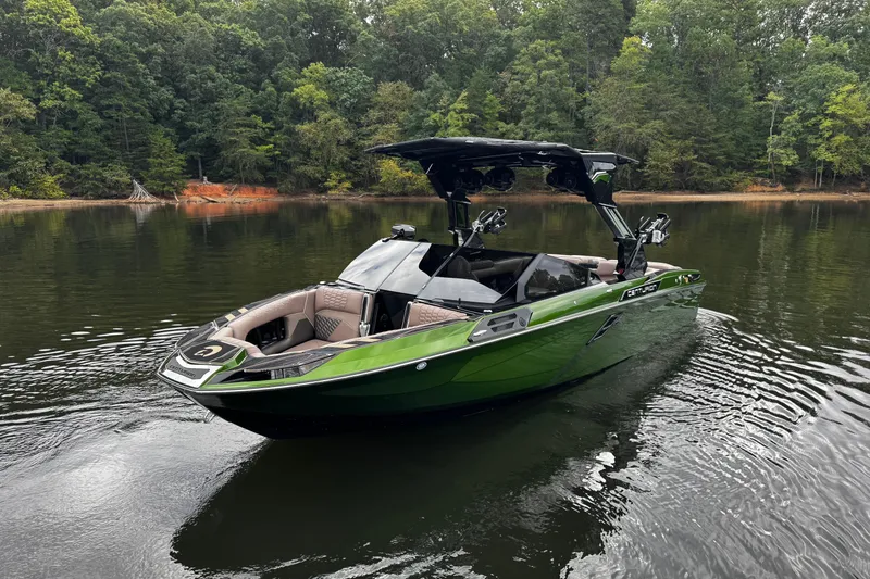 Slide: The Image of 2026 Centurion Ri245 boat in a serene lake setting with lush forest backdrop. - 1