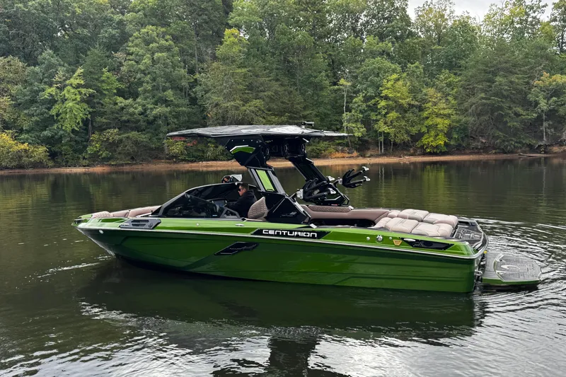 Slide: The Image of 2026 Centurion Ri245 boat in green on a calm lake, surrounded by lush trees. - 4