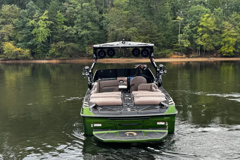 Slide: The Image of 2026 Centurion Ri245 boat on a calm lake, surrounded by lush green trees. - 6
