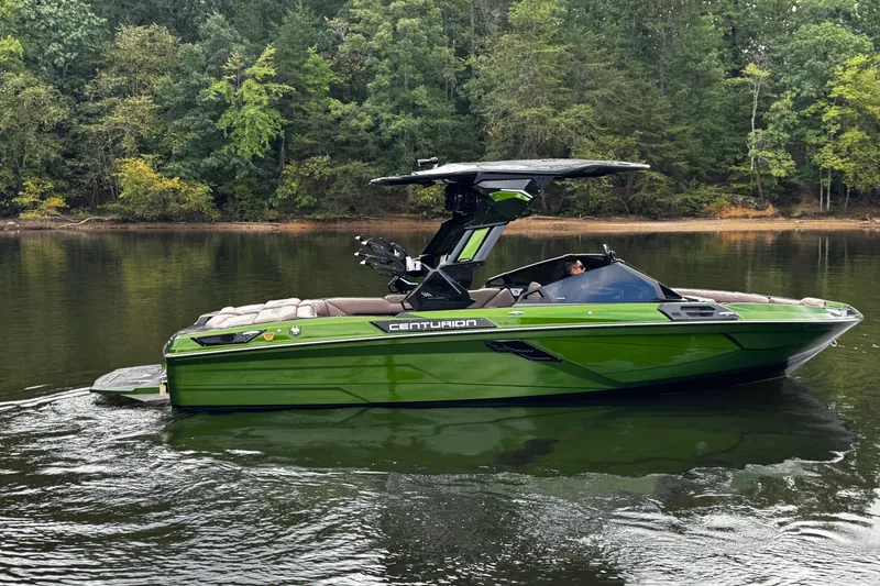 Slide: The Image of 2026 Centurion Ri245 boat in green on a calm lake with forested background. - 9