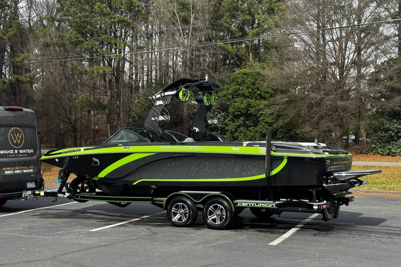 Slide: The Image of 2015 Centurion Enzo FS44 boat with vibrant green accents on a trailer in a parking lot. - 13